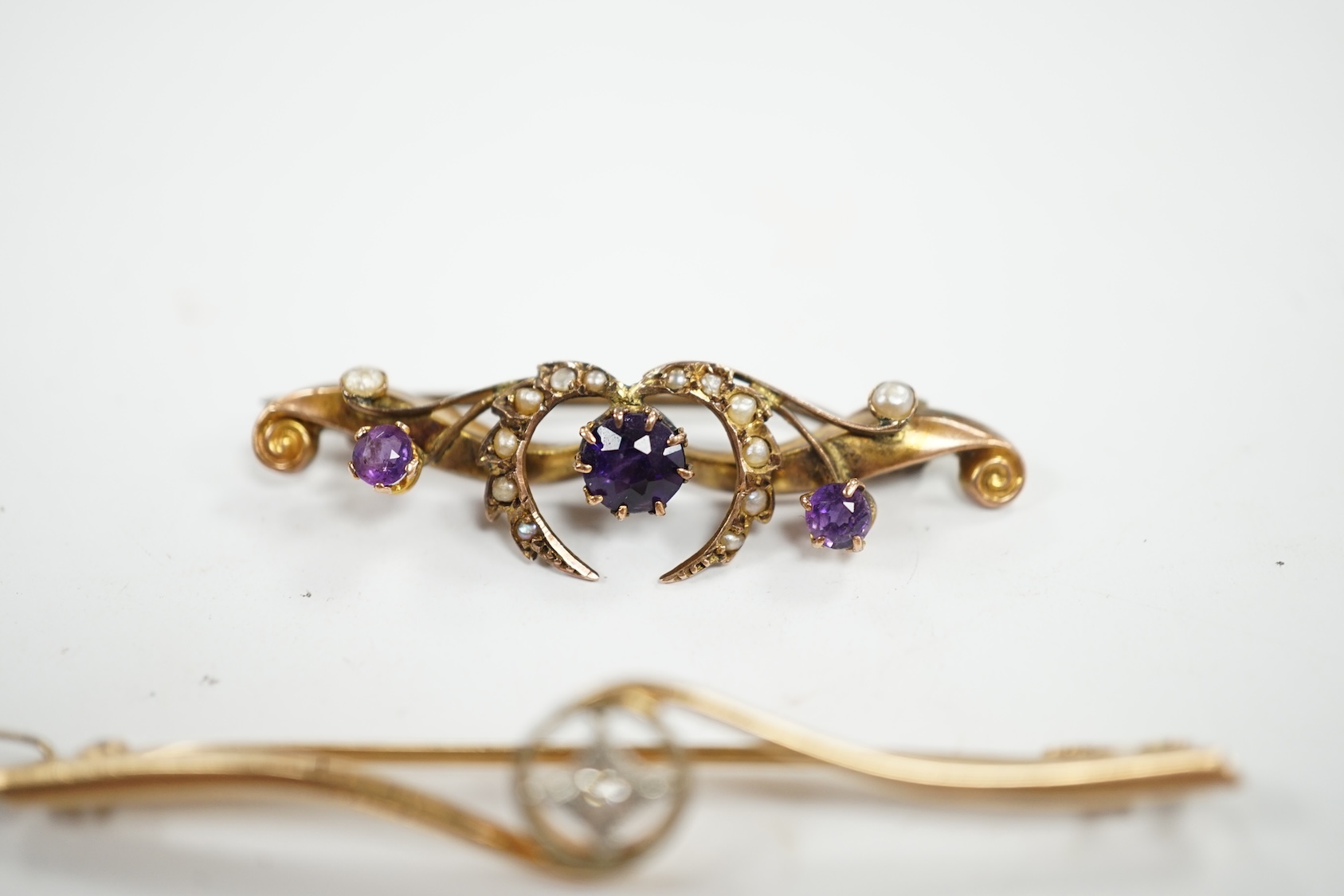 An Edwardian 15ct and diamond set crossover bar brooch, 57mm, gross weight 3.9 grams, together with a similar 9ct gold, amethyst and seed pearl set bar brooch, gross weight 2.3 grams. Condition - fair